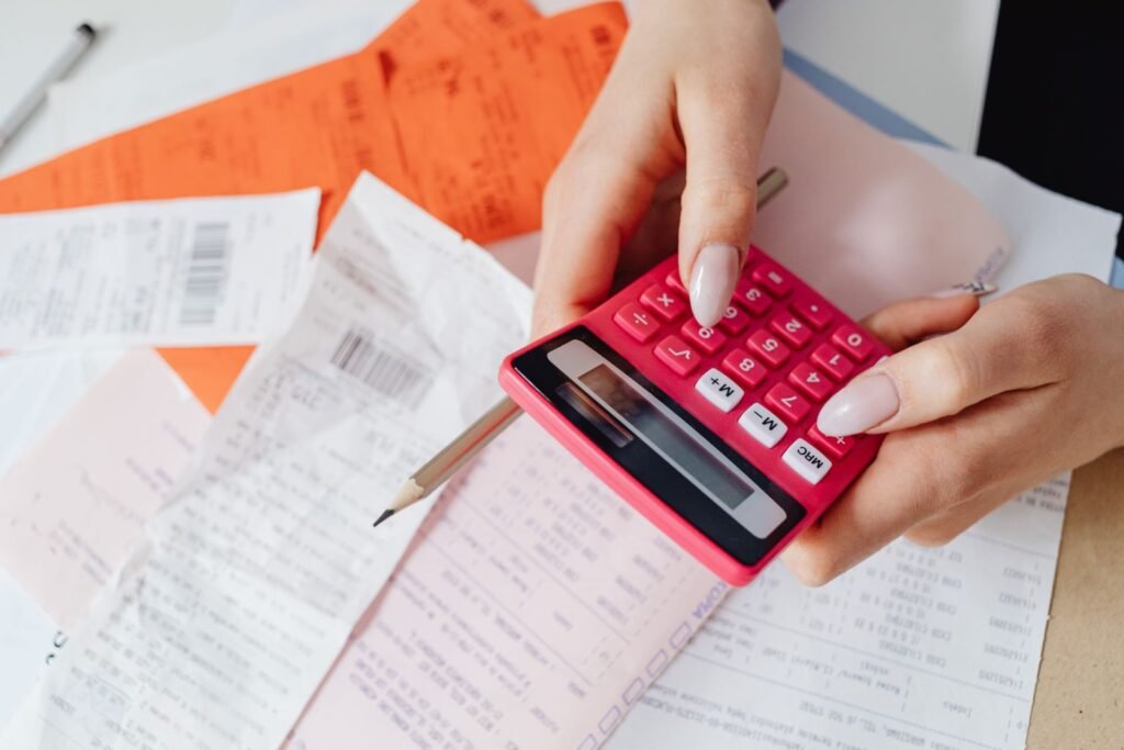 Persona cuadrando números con una calculadora entre recibos y documentos.