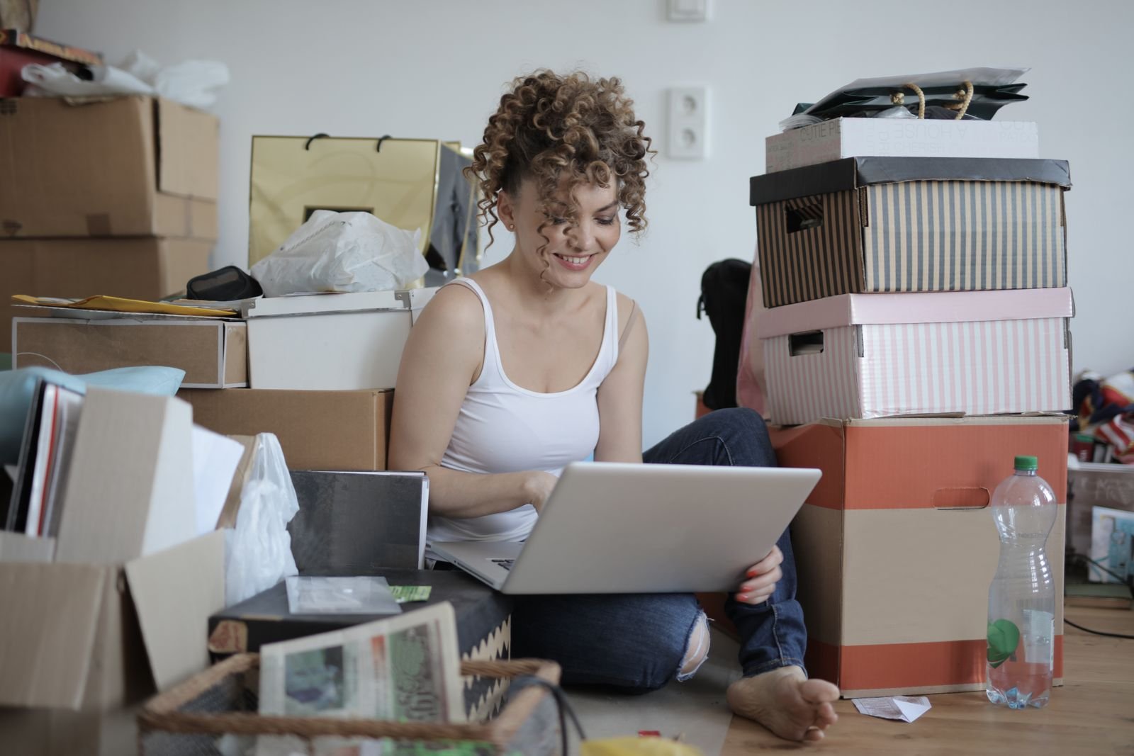 Mujer haciendo pedidos con el portátil rodeada de cajas de cartón.
