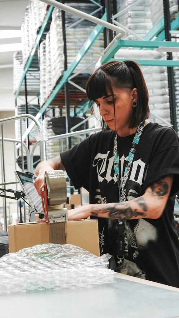 Trabajadora precintando una caja de cartón para enviarla.